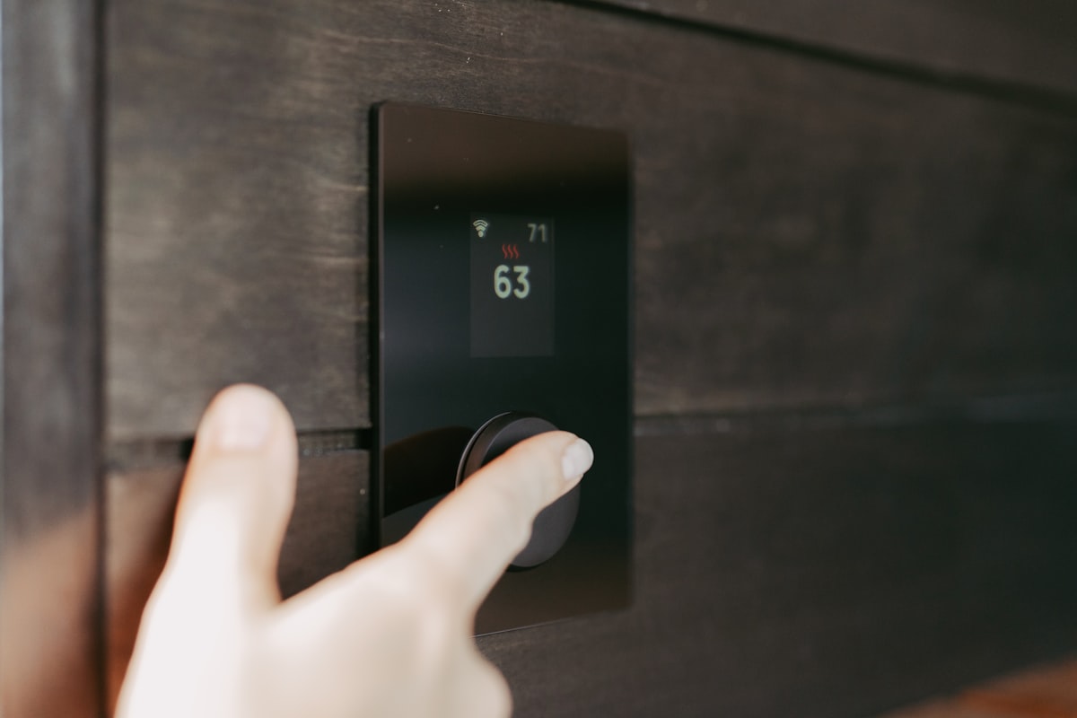 Hand adjusting a digital smart thermostat on a wall for energy efficiency