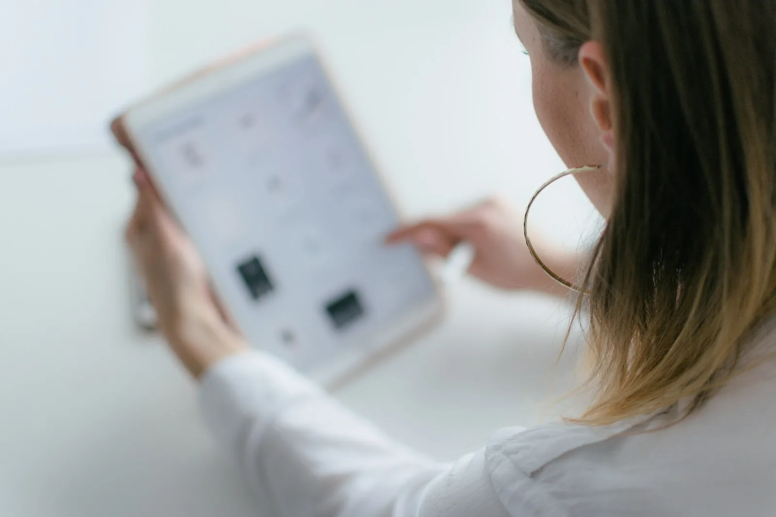 A person using a tablet with a smart home dashboard in a warm lamp-lit living space