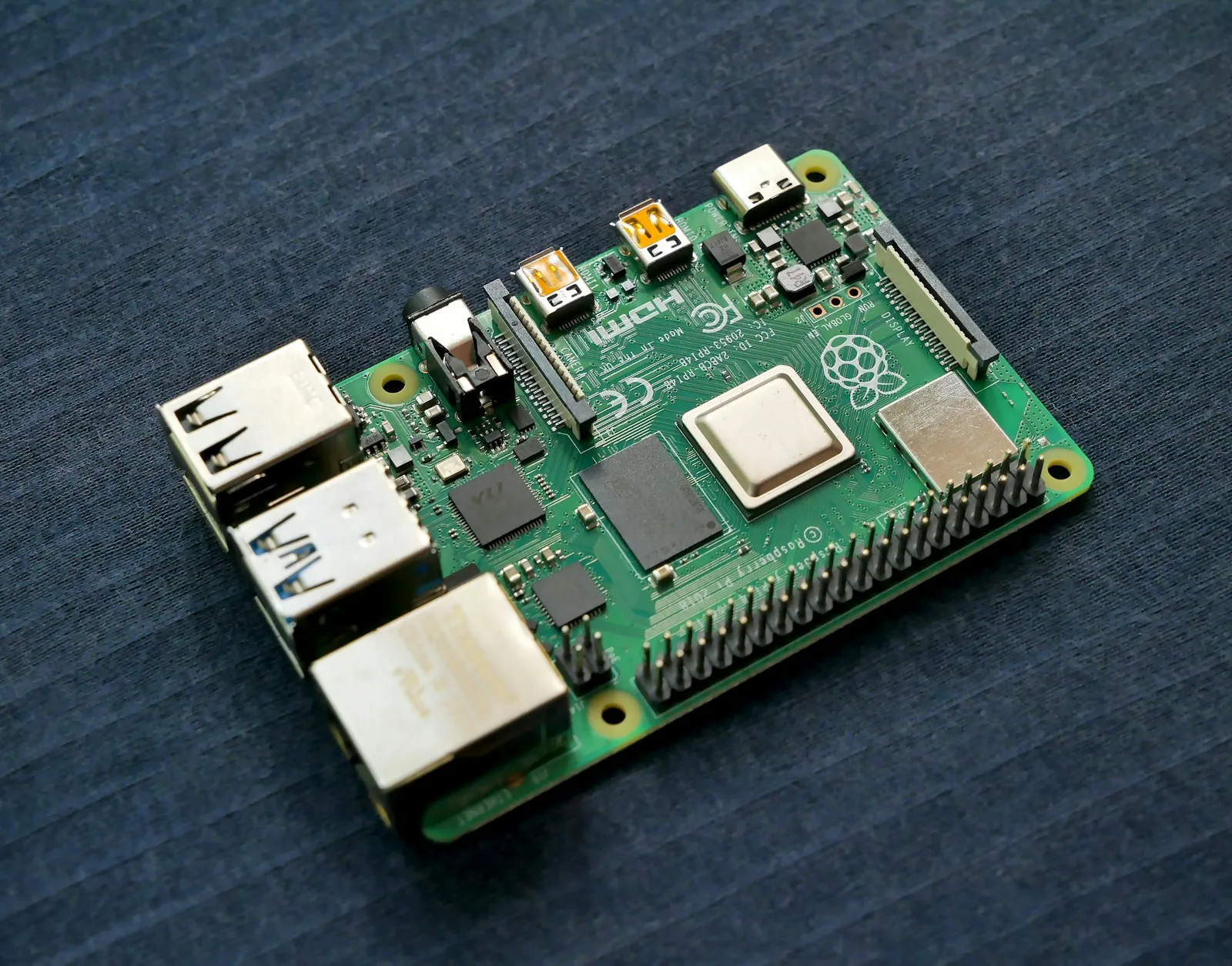 Close-up of a Raspberry Pi single-board computer next to a home router with green status lights on a shelf