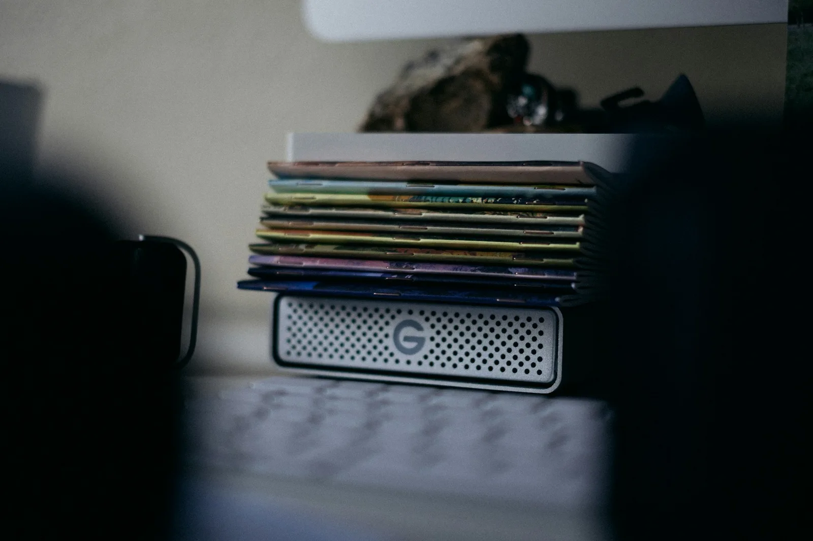A stack of two external hard drives beside a small computer with a glowing status light on a shelf