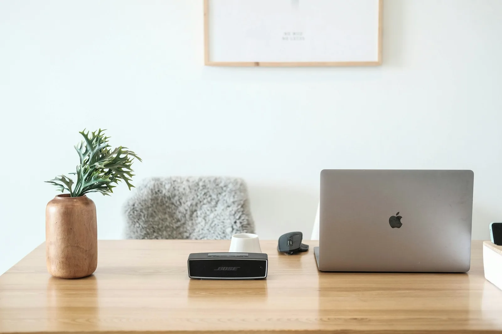 A small fanless mini PC sitting on a wooden desk beside a monitor, warm morning light in a tidy home office