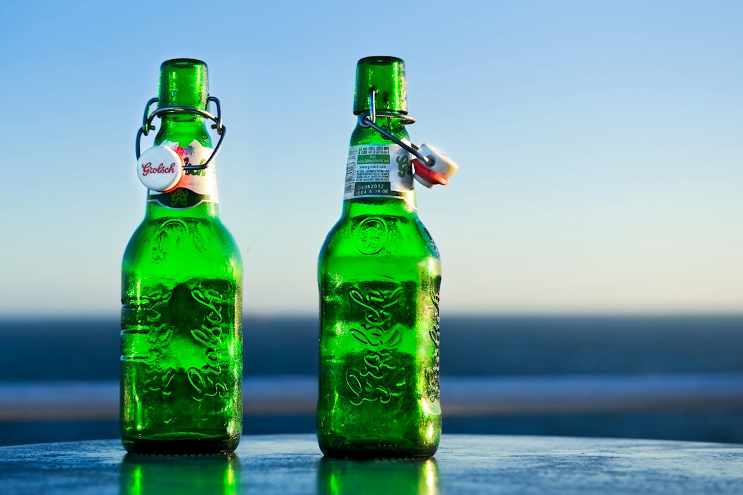 Green Grolsch-style swing-top bottles of homemade ginger beer on a wooden surface