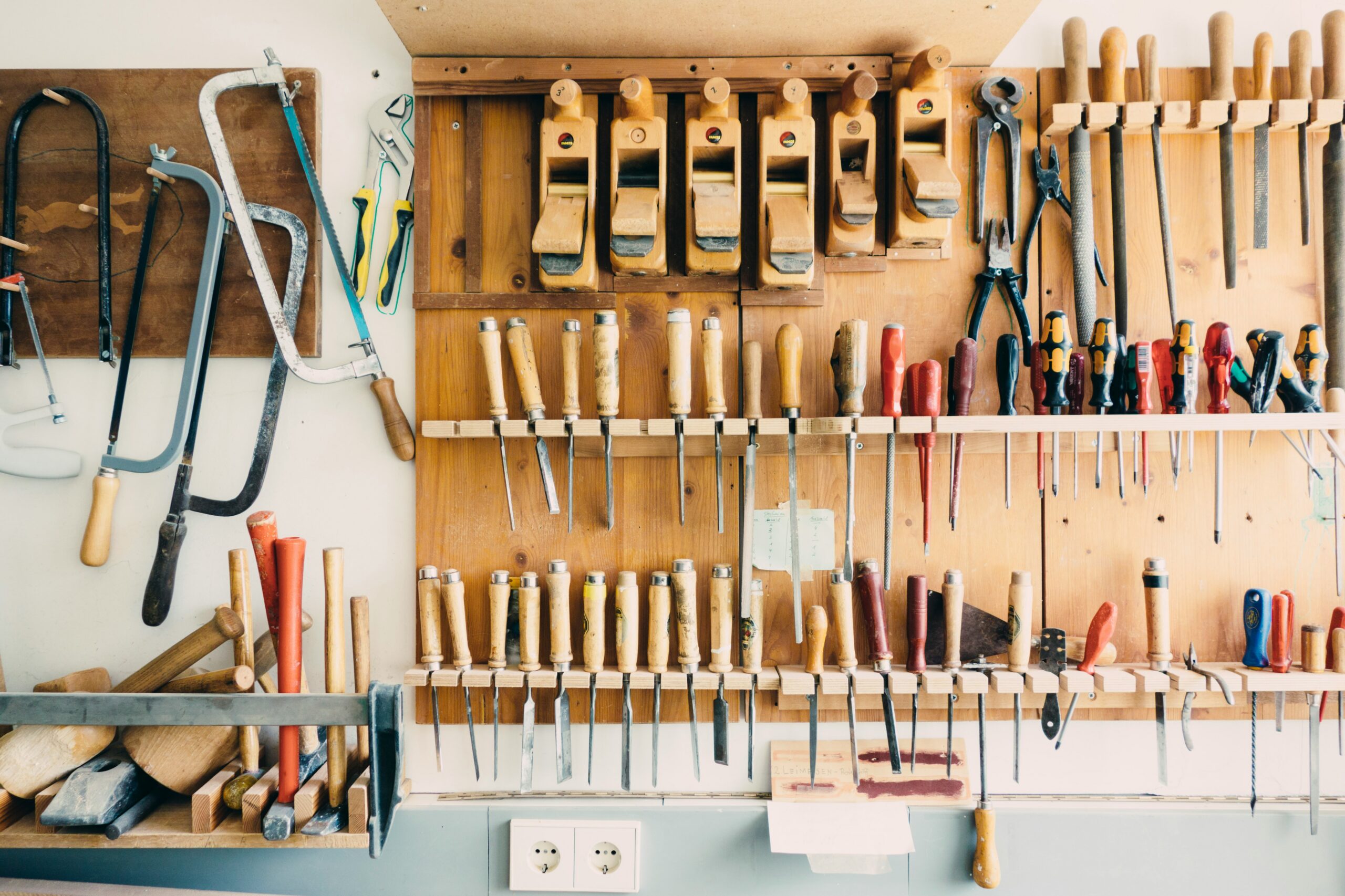 A meticulously organized tool library wall with labeled power tools and hand tools, each in a designated slot on a brightly lit rack