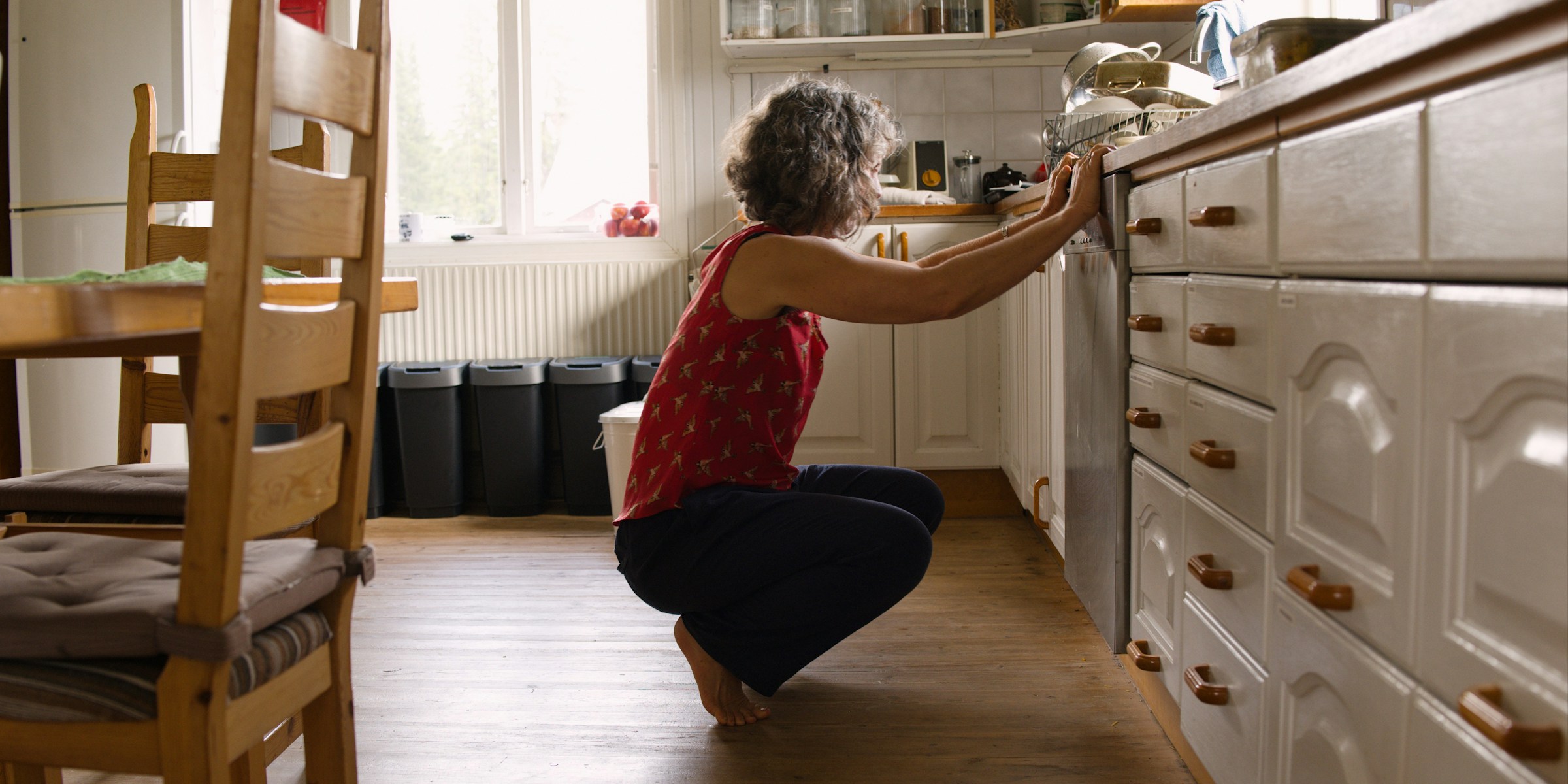 An adult practicing a balance squat in a bright home kitchen